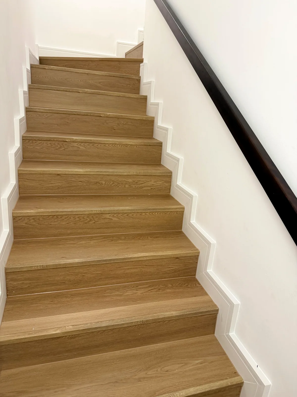 Stair cladding Tilal Al Ghaf villa with light oak SPC and white skirting following the stairs