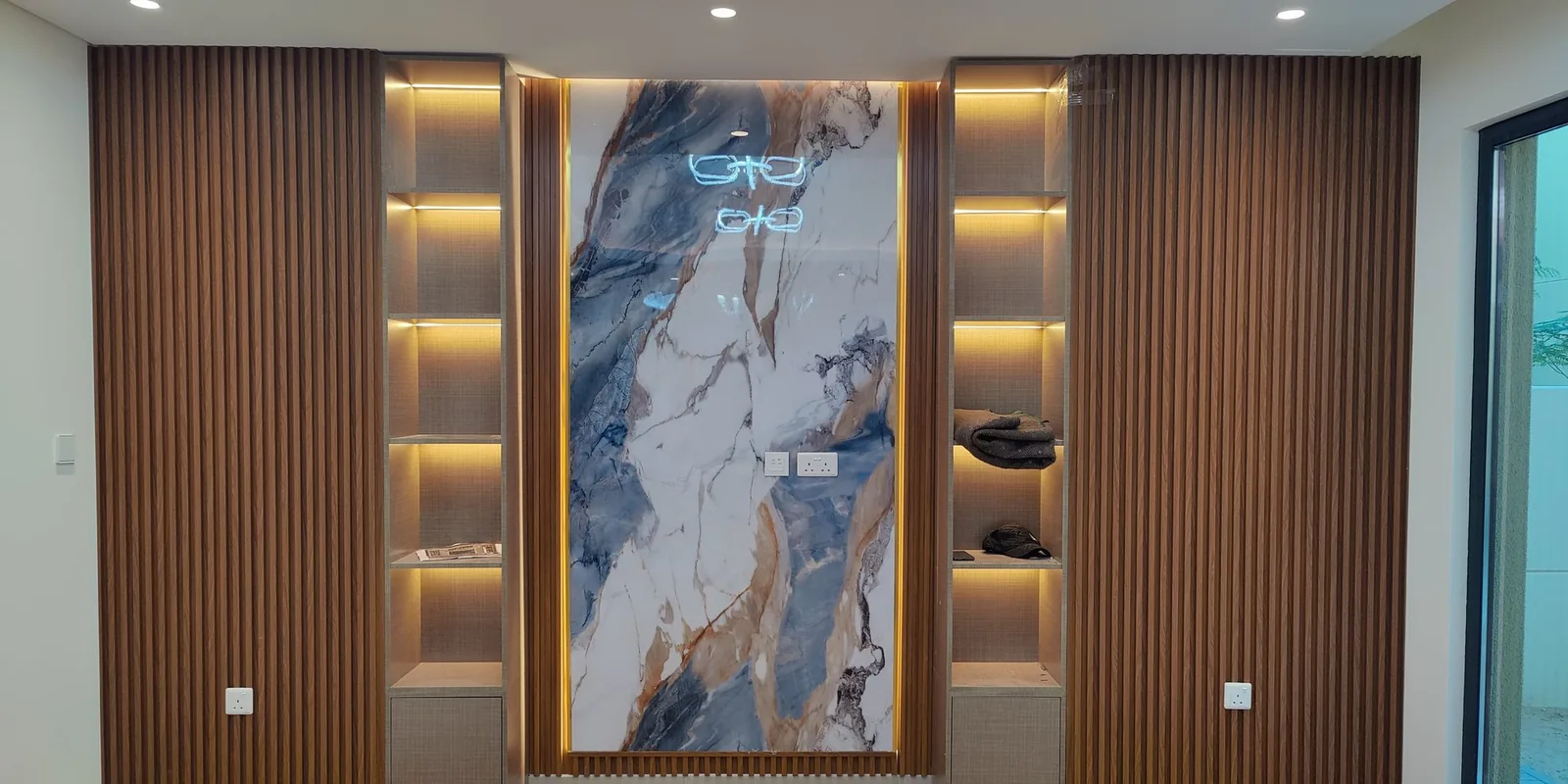 Fluted wood slat wall with marble art panel and lit shelving